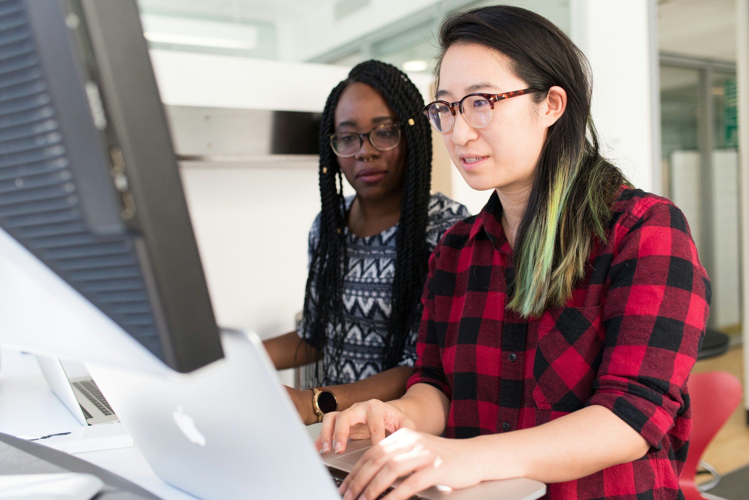 Two professionals collaborating at a computer in an office setting