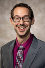 Professional smiling man in gray suit and pink shirt wearing glasses