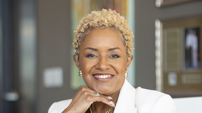 Smiling mature professional woman in white blazer with curly blonde hair