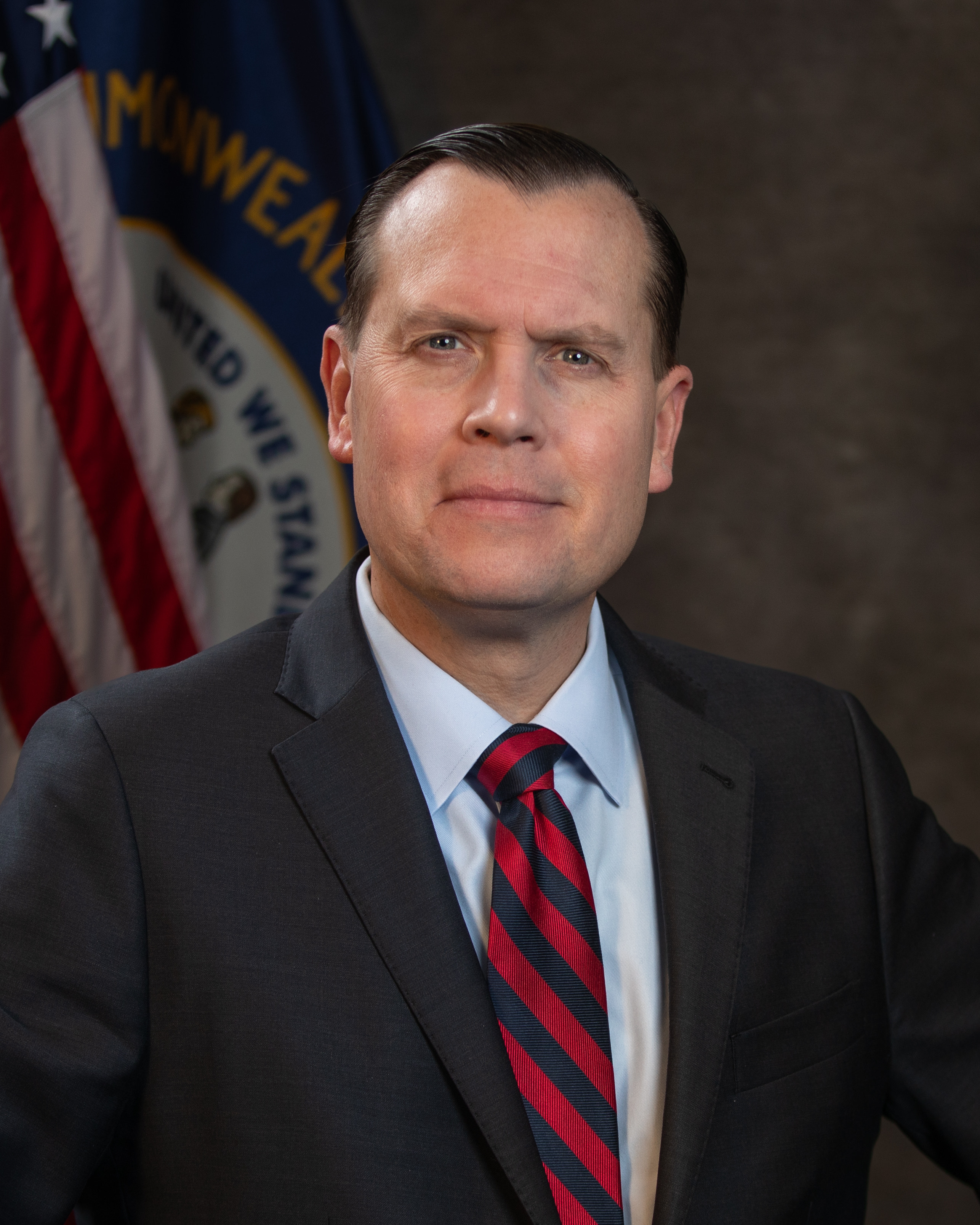 Government official in dark suit posing before American flag