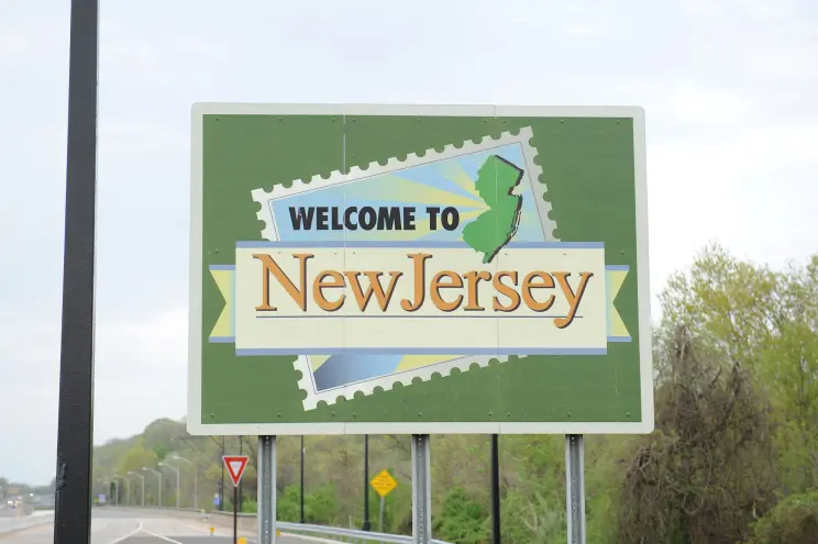 Welcome to New Jersey roadside sign featuring state outline and green background