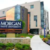 Morgan State University exterior sign on modern building with blue glass panels and purple flowers