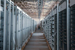 Industrial electrical substation with rows of white and black control cabinets and distribution panels in a warehouse facility