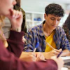 Diverse students collaborating on a group project with laptop in classroom setting